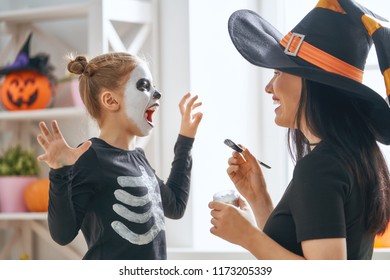 Happy Family Preparing For Halloween! Young Mom And Her Kid In Carnival Costumes Celebrate The Holidays.