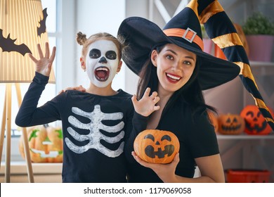 Happy Family Preparing For Halloween! Young Mom And Her Kid In Carnival Costumes Celebrate The Holidays.