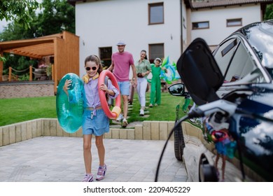 Happy family preparing for holiday while their electric car charging. - Powered by Shutterstock