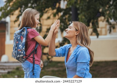 Happy family preparing for school. Little girl with mother. Mother saying goodbye to her daughter at school. Beginning of lessons. First day of fall. - Powered by Shutterstock