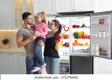 Happy Family With Products Near Open Refrigerator In Kitchen