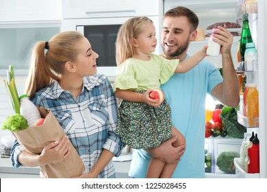 Happy Family With Products Near Refrigerator In Kitchen