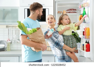 Happy Family Putting Products Into Refrigerator In Kitchen