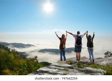 Happy Family With Raised Hands Enjoying Time Together  On Top Of The  Mountain Over The Clouds. Blue Ridge Parkway, Close To Blowing Rock,  North Carolina, USA.