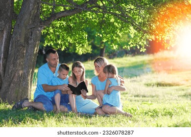 happy family reading bible in nature - Powered by Shutterstock