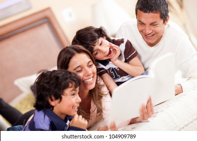 Happy Family Reading A Book In Bed