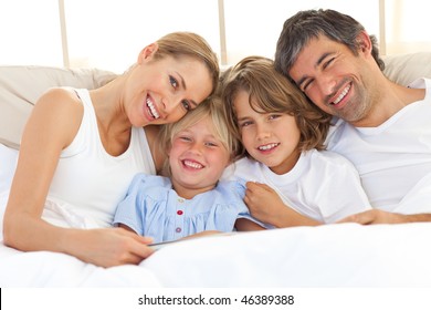 Happy Family Reading A Book  Lying In Bed