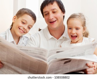 Happy Family Reading A Newspaper. Father With Daughter And Son