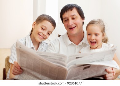 Happy Family Reading A Newspaper. Father With Daughter And Son