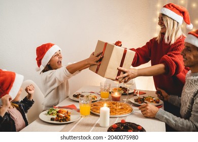 Happy Family Receiving Gifts During Vegan Christmas Dinner Waring Santa Claus Hats - Focus On Girl Face