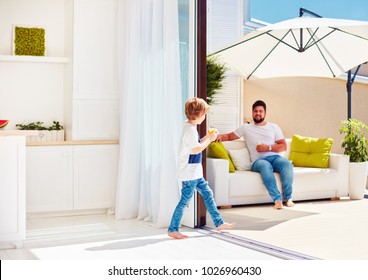 Happy Family Relaxing On Rooftop Patio With Open Space Kitchen At Warm Summer Day