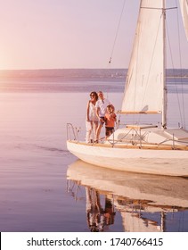 Happy Family Relaxing On Sailboat At Sunset