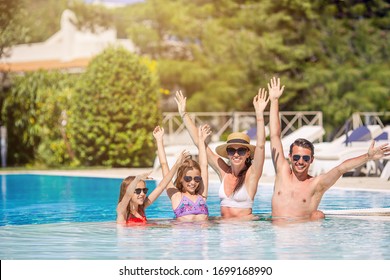 Happy Family Relaxing In Swimming Pool