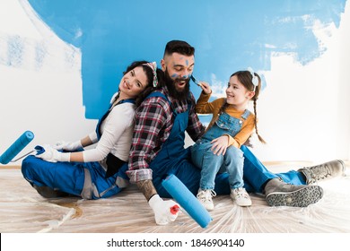 Happy Family Renovating Their Home. They Are Painting A Wall Together.