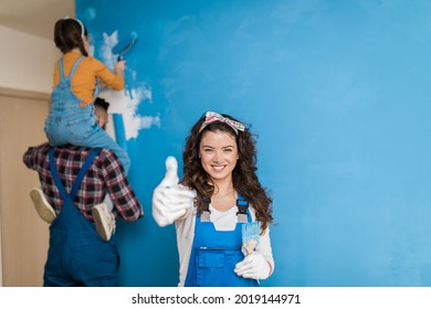 Happy Family Renovating Their Home. They Are Painting A Wall Together.