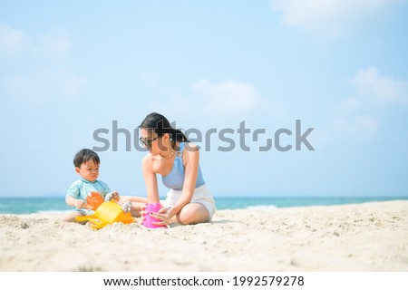 Happy family resting at beach in summer, Mother and baby feet at the sea foam at the sunlight water is moving