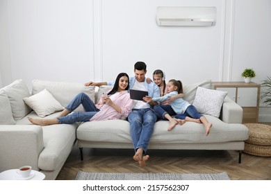 Familia feliz descansando bajo aire acondicionado en la pared blanca en casa