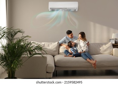Familia feliz descansando bajo aire acondicionado en la pared beige en casa