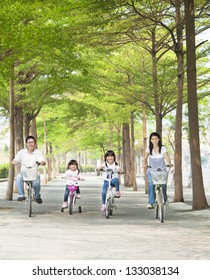 Happy Family Riding Bicycle In The Park