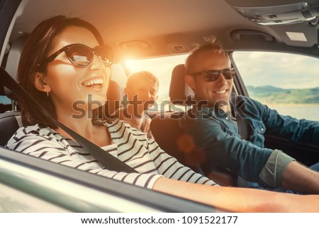 Happy family riding in the modern car. Couple with a little son on the backseat. Family values and car traveling concept.