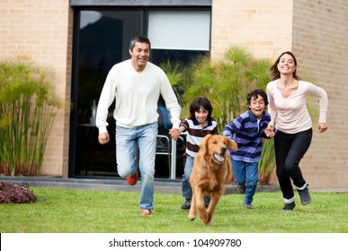 Happy Family Running After A Dog Outdoors