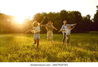 Happy family running and having fun in summer park enjoying sunny day in nature. Mother, father and their cheerful children boy and girl walking on green grass outdoors at sunset together. - Powered by Shutterstock