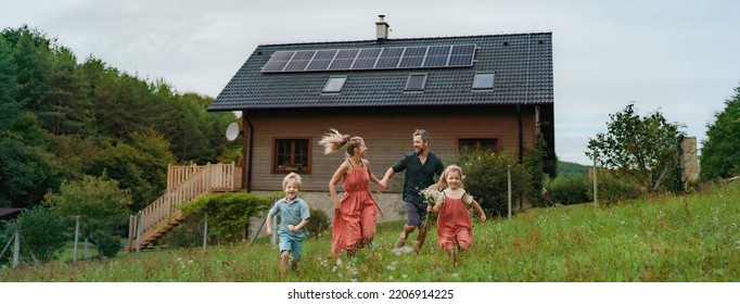 Happy family running near their house with solar panels. Alternative energy, saving resources and sustainable lifestyle concept. - Shutterstock ID 2206914225