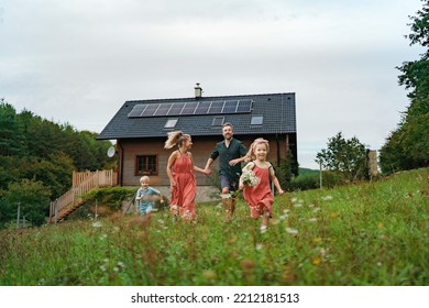 Happy family running near their house with solar panels. Alternative energy, saving resources and sustainable lifestyle concept. - Shutterstock ID 2212181513