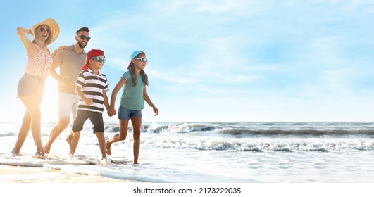 Happy family running on sandy beach near sea, space for text. Banner design - Powered by Shutterstock