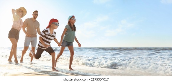 Happy family running on sandy beach near sea, space for text. Banner design - Powered by Shutterstock