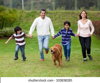 Happy family running outdoors chasing a dog