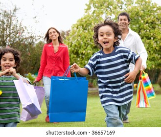 Happy Family Running Outdoors With Shopping Bags