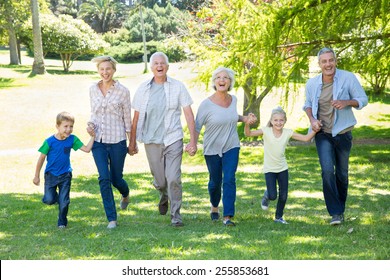 Happy Family Running In The Park On A Sunny Day