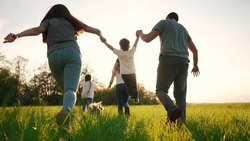 Happy Family Running In The Park In Summer. Mom And Dad Hold Their Son By The Hands Run Throw Up In The Forest Park On The Grass In The Summer. Happy Family Lifestyle Kid Dream Concept