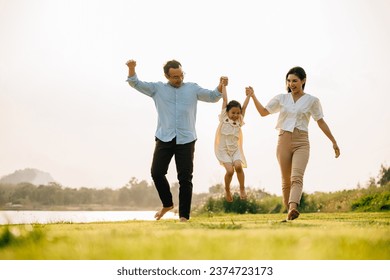 Happy family running through a beautiful green field on a sunny summer day, enjoying the freedom and beauty of nature together, Happy Family Day Concept - Powered by Shutterstock