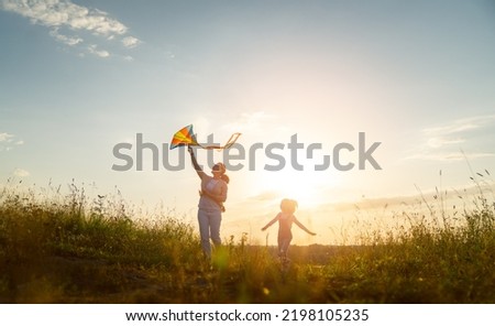 Happy family running through field with kite.