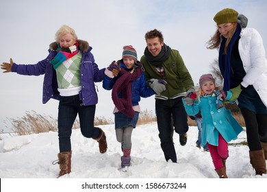 Happy family running through snow on winter day Stock Photo