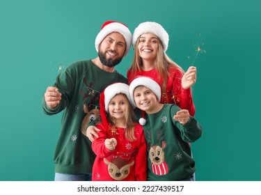 Happy family in Santa hats with Christmas sparklers on green background - Powered by Shutterstock