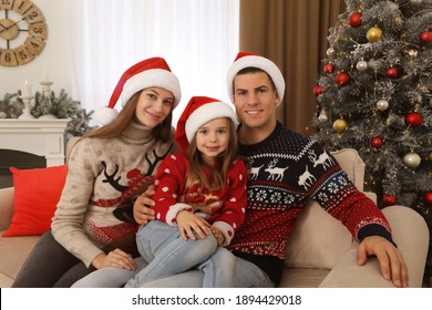 Happy Family In Santa Hats Near Christmas Tree At Home