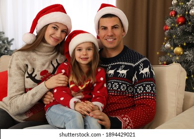 Happy Family In Santa Hats Near Christmas Tree At Home