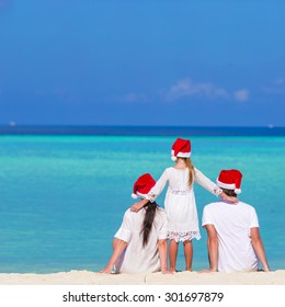 Happy Family In Santa Hats On Beach During Christmas Vacation