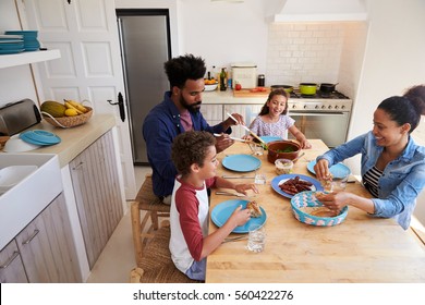 Happy Family Serving Food At Their Kitchen Table