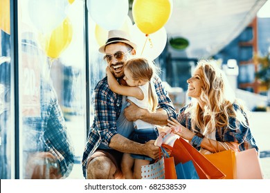 Happy Family With Shopping Bags And Ballons Walking On Street.