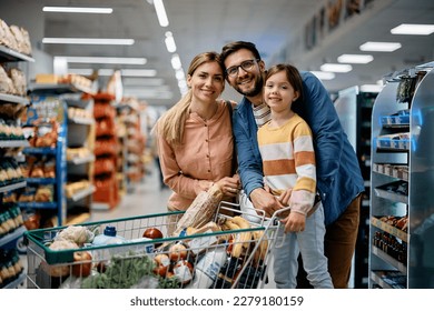Happy family with shopping cart full of groceries in supermarket looking at camera. - Shutterstock ID 2279180159