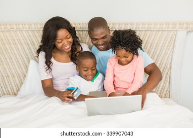 Happy Family Shopping Online With Laptop On Bed