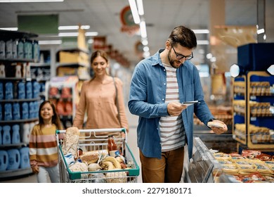 Happy family shopping in the supermarket. Focus is on father going through grocery list.  - Powered by Shutterstock