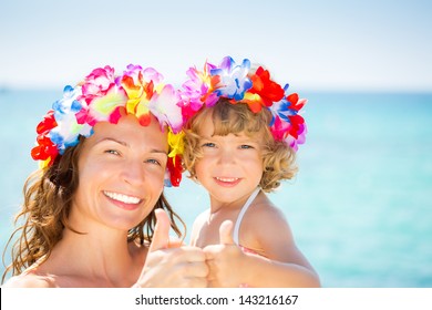 Happy family showing thumb up sign against blue sea background. Summer vacations concept