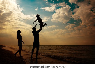 Happy Family Silhouettes On Beach At Sunset