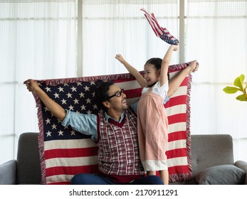 Happy family, Single father and cute little daughter sitting on sofa at home with flags of United States of America, celebrating independence Day. 4th of July, Patriotic US holiday,