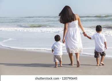 A Happy Family Of Single Hispanic Mother, And Two Boys Sons Children, Walking Holding Hands In The Sea & Sand Of A Sunny Beach